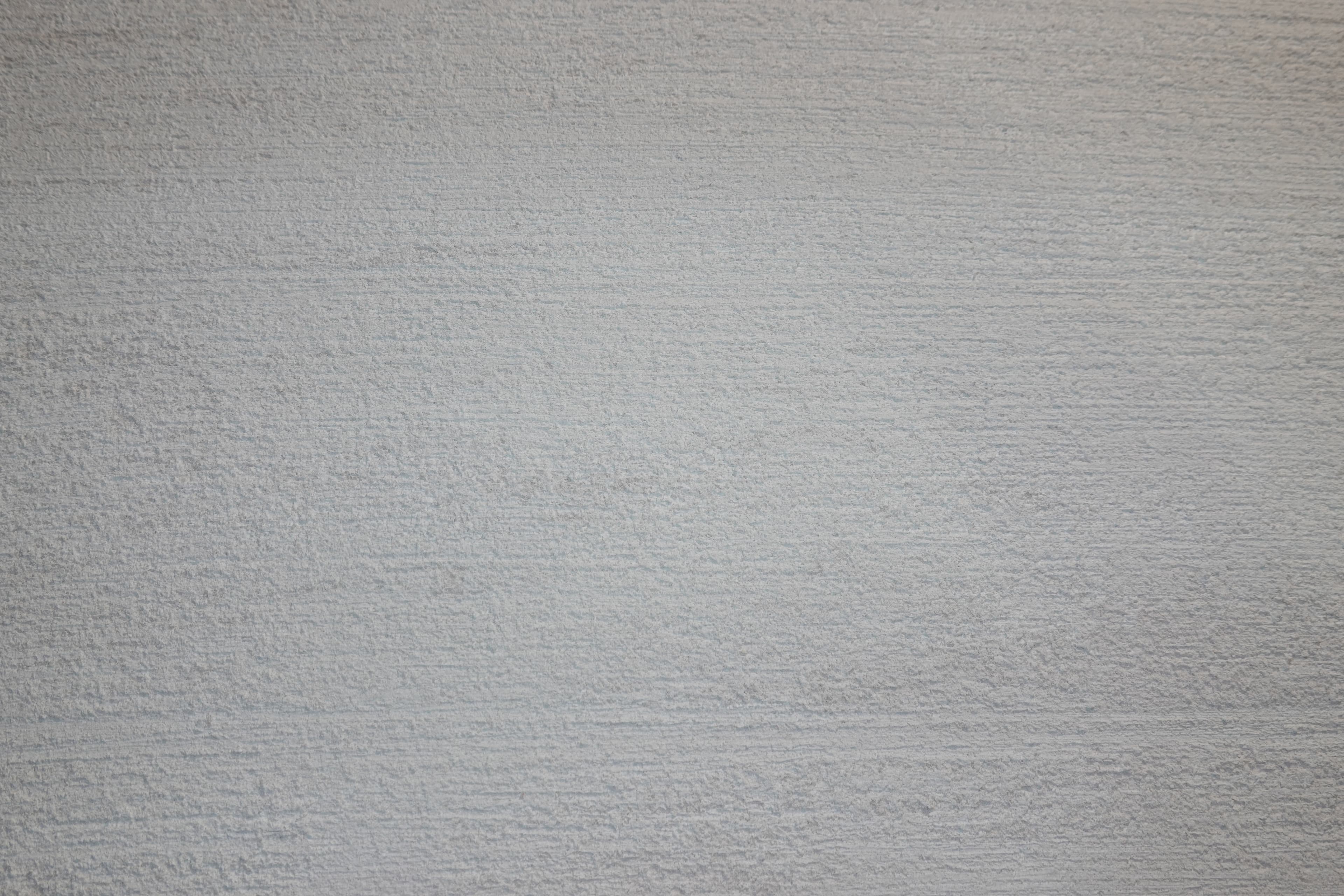 A Travertino lime-plaster surface in a pale, cool gray-white, worked to a fine, even, closely ridged texture.